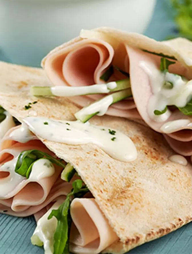 Mitades de pan pita rellenas con pechuga de pavo, arúgula y salsa tzatziki